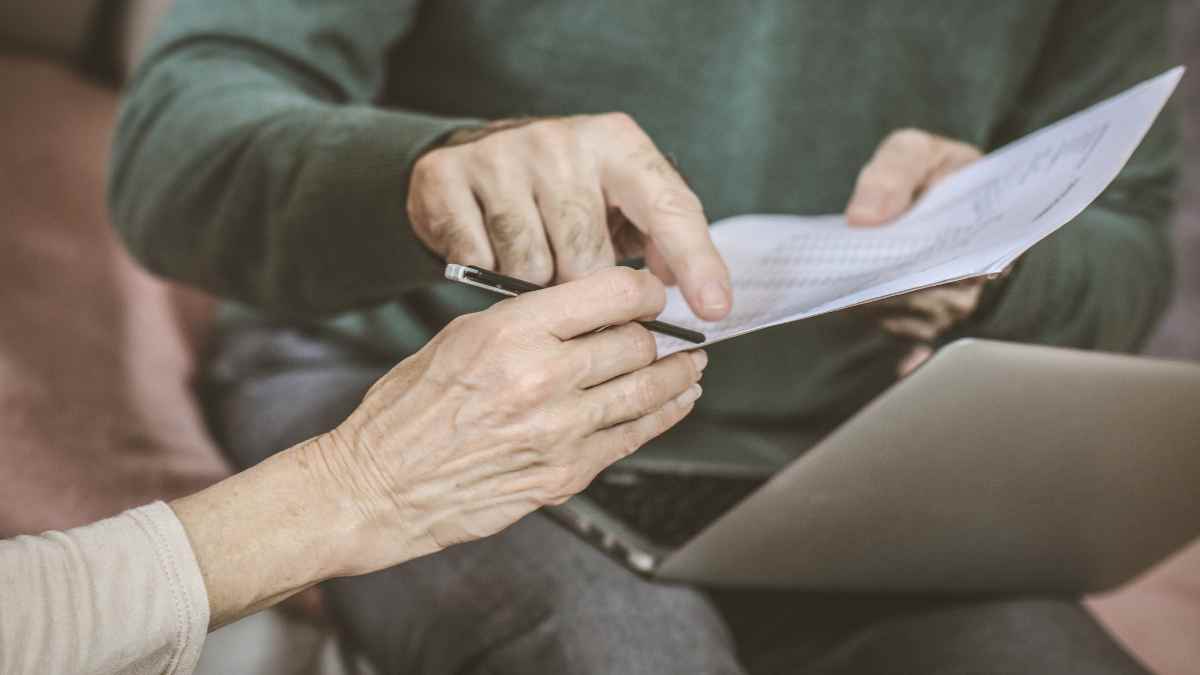 Two borrowers reading through a contract to see the lending requirements.